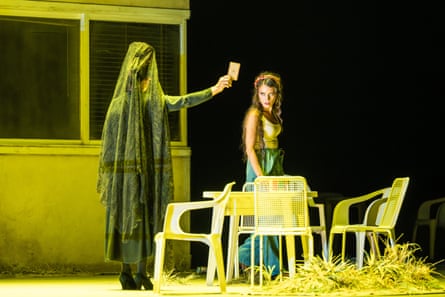 In a Carmen opera scene, a veiled figure holds up a mirror toward a woman