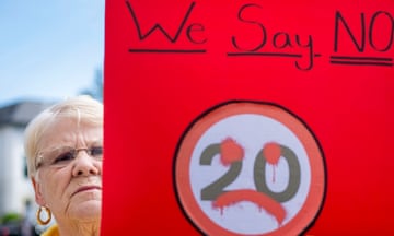 A woman holds a placard with a sad face sprayed over a 20mph sign