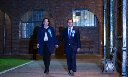 Berkner and Jenrick walk hand in hand. They are both wearing blue Conservative rosettes