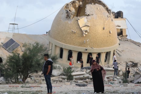 People stand by a destroyed mosque following an Israeli airstrike in the southern Gaza Strip city of Khan Yunis.