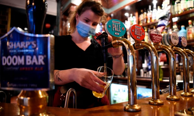 A server wearing a face mask pours a pint in a pub in London on 3 November 2020 on the eve of a second national lockdown due to Covid.