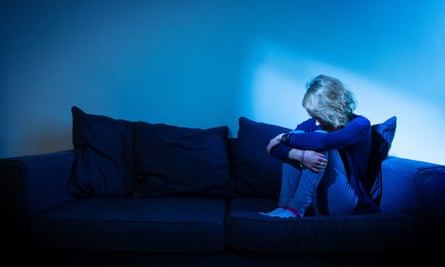 woman sitting on a sofa looking sad in the dark