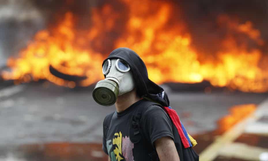 An anti-government protester in front of burning barricade in Caracas.