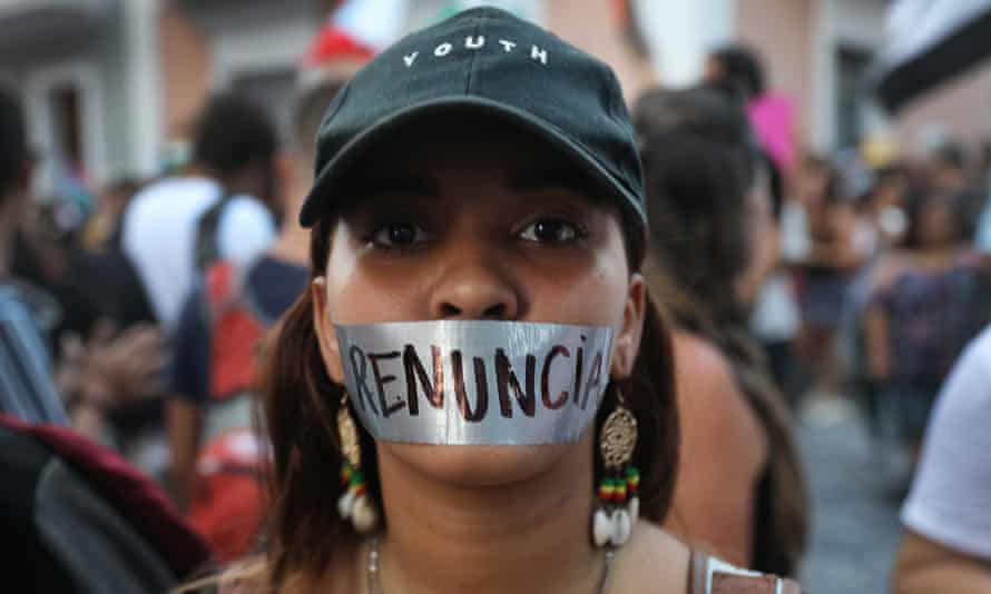 A woman wears tape over her mouth reading ‘resignation’ in Spanish in Puerto Rico, on 16 July.