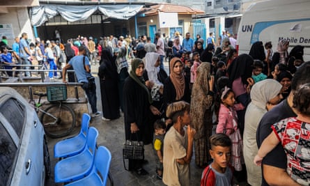 People form a queue with a UN-branded van in the background