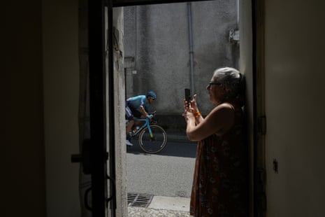 A woman takes images with her mobile phone as Kazakhstan’s Andrey Zeits passes though the town of Saint-Pe-de-Bigorre.