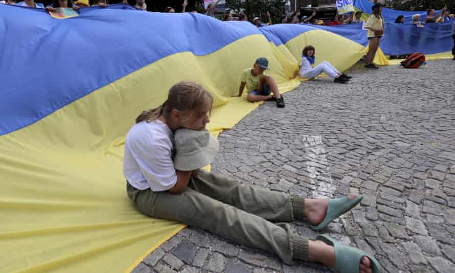 A girl sits on a huge Ukrainian flag during the demonstration against the war in Ukraine in Garmisch-Partenkirchen, Germany.
