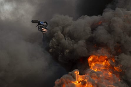 A journalist films amid tyres set on fire by anti-government protesters during a demonstration in the southern Iraqi city of Basra in January 2020.