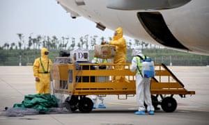 In this photo taken on 16 September 2020, ground crew spray disinfectant on luggage being unloaded from a Boeing 737-800 operated by South Korean carrier T’way after landing at Wuhan’s Tianhe International Airport, in China’s central Hubei province.