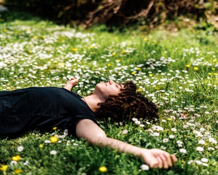 Boy with curly hair lying on grass and little daisies