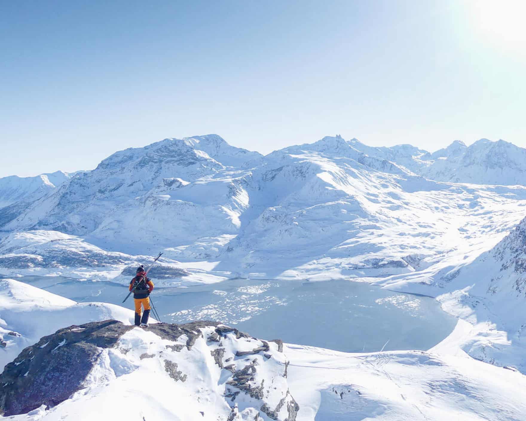 Val Cenis - a lone skier on a rock looking out at a dramatic snowy mountainscape