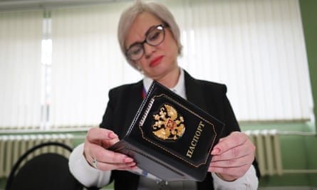 An election official inspects the passport of a person voting.