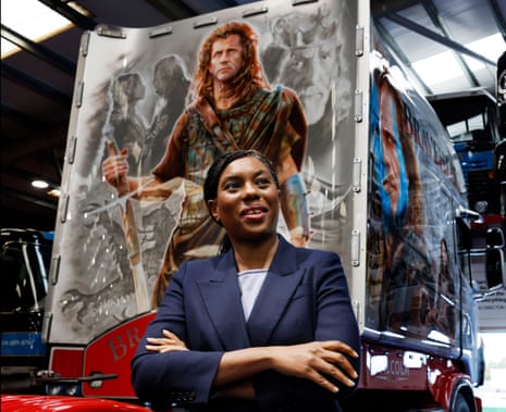 Kemi Badenoch standing in front of a truck decorated with a Braveheart mural.