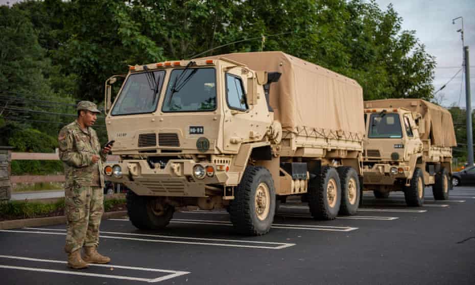 A US Army National Guard Soldier takes a phone call as he stands next to high-water rescue trucks in Connecticut on August 2021.