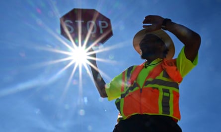 Man wearing fluorescent yellow vest and hat with stop sign