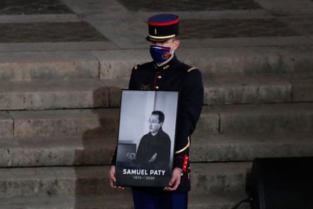 A Republican Guard holds a portrait of Samuel Paty