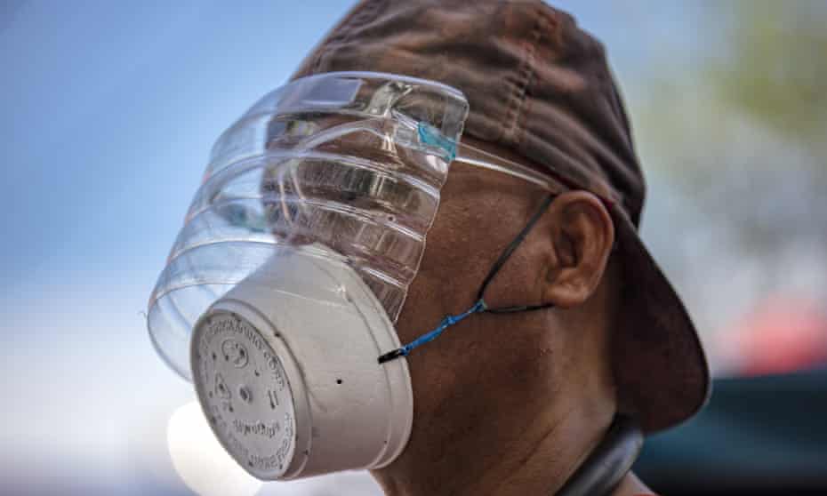 A man is seen wearing a makeshift mask made out of a styrofoam cup and a face shield made out of a plastic bottle to protect against Covid-19 in Manila