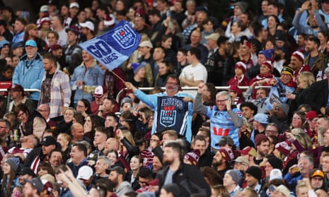 A NSW fan waves a flag in the crowd among Qld fans