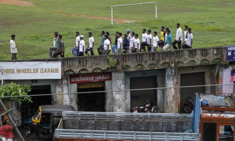 Men in white T-shirts parade training at a football ground