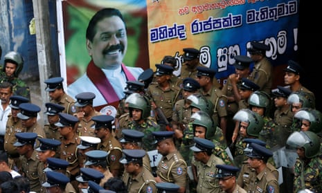 Sri Lankan police and special forces stand guard next to a poster of the newly appointed prime minister, Mahinda Rajapaksa, in Colombo