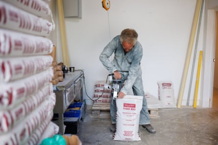 A man uses a piece of machinery to seal a flour sack