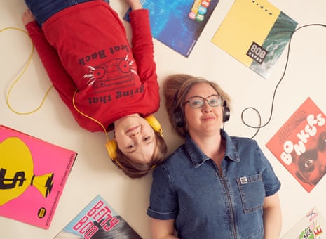 Jude Rogers and her son lying on the floor in opposite directions but with their heads next to each other, both with headphones on, music album covers around them