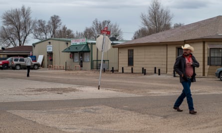 A man wearing a cowboy hat and boots walks down a street in Cactus, Texas.