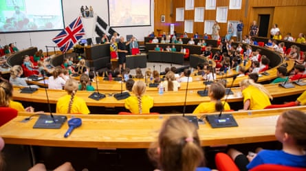 Children seated at Truro county hall with union jack and Cornish flags on display.