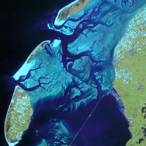 This satellite image shows the ever-moving sandbanks in the shallow Wadden Sea in the north of the Netherlands. This unique region is one of the largest wetlands in the world. As this satellite image shows, the sandbanks are bordered by relatively deep channels and gullies, which provide a route for boats crossing between the islands and mainland.
