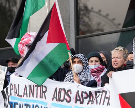 NHS workers in keffiyehs and masks, holding a Palestinian flag and a banner