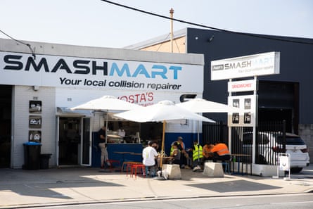 Exterior shot of a takeaway sandwich shop, with outdoor seating, located at a smash repair shop