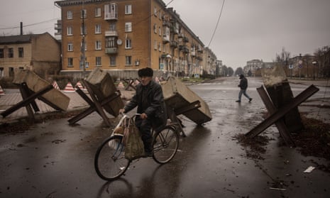 A resident rides his bike through street barricades in Bakhmut, Ukraine. 