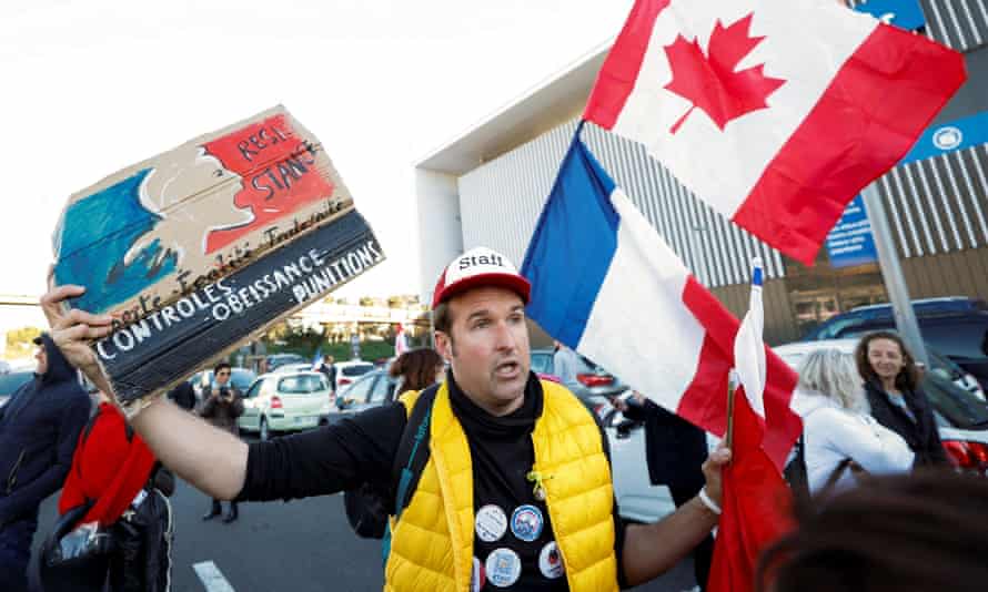 Un manifestant à Nice portant des drapeaux français et canadiens 