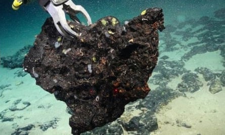 Un brazo robótico levanta un trozo de roca del fondo del océano