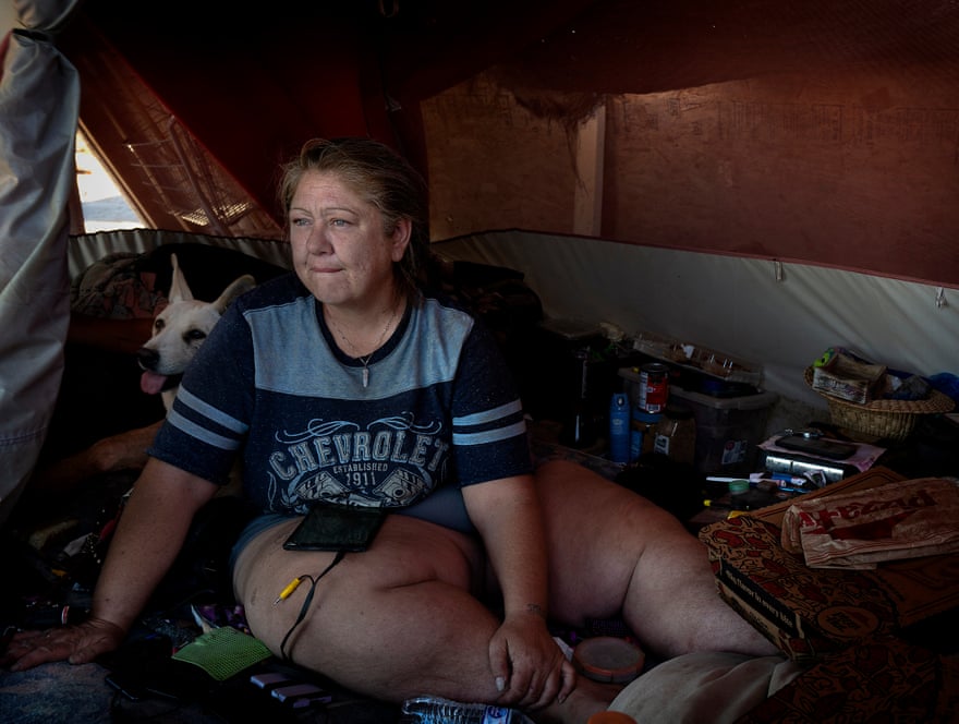 A woman sits inside a tent with her dog