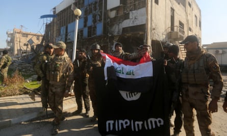 Iraqi security forces place the Iraqi flag above the Islamic State group flag as they pose for a picture on 28 December 2015 in front of the Anbar police headquarters after they recaptured the city of Ramadi, the capital of Iraq’s Anbar province, about 68 miles west of Baghdad.