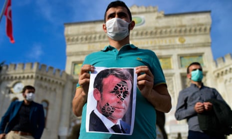 A protester in Istanbul holds a picture of Emmanuel Macron, which has been defaced with a shoe print