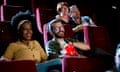 Couple watching a comedy film and enjoying their date at the cinema<br>Multi-ethnic couple watching a comedy movie at the cinema and enjoying.