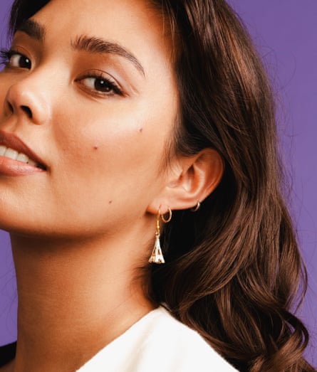 A model poses with her head back and looks at the camera. She’s wearing Eiffel Tower earrings