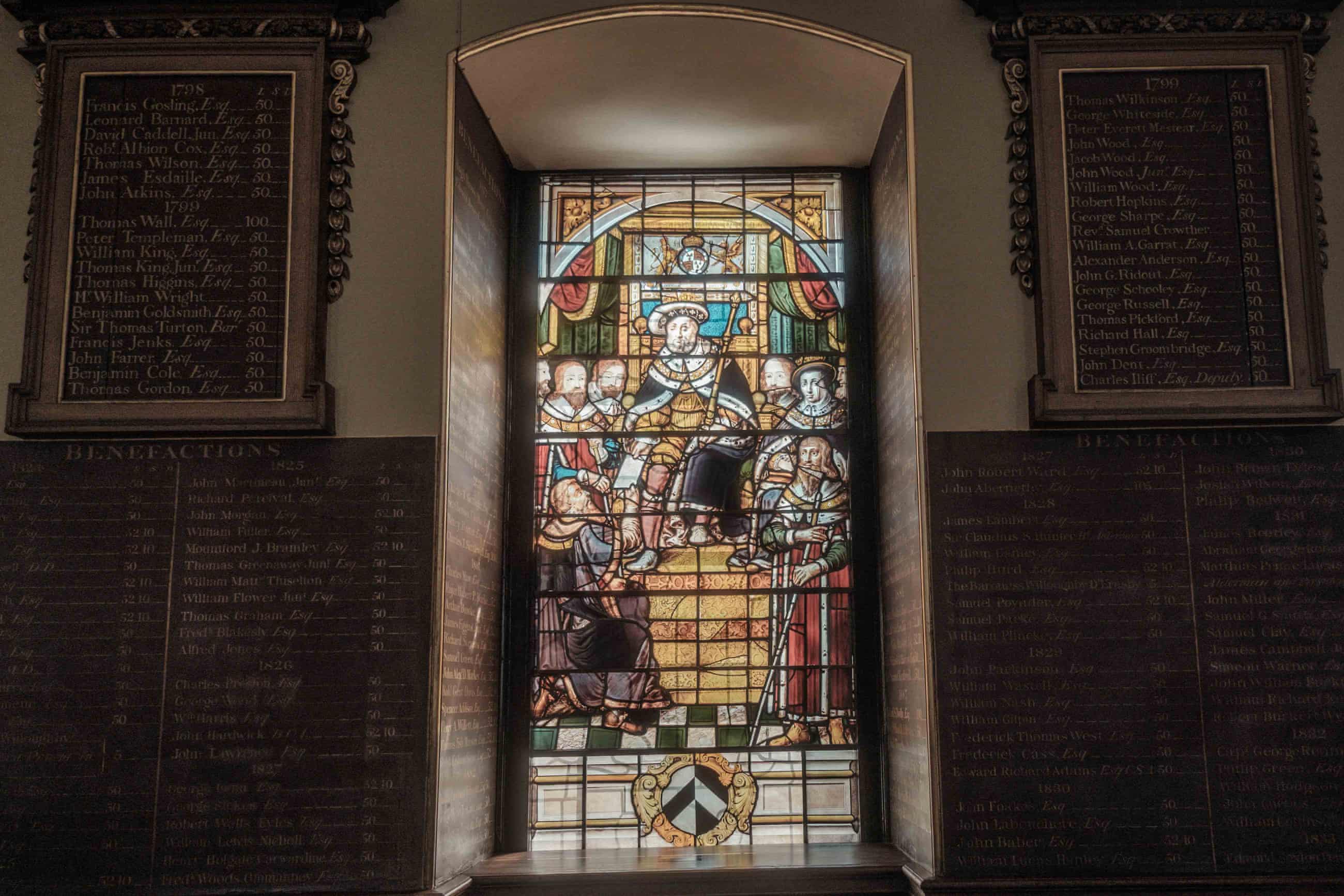 A stained glass window depicting a monarch in the Great Hall. Surrounding the window are more commemorative boards