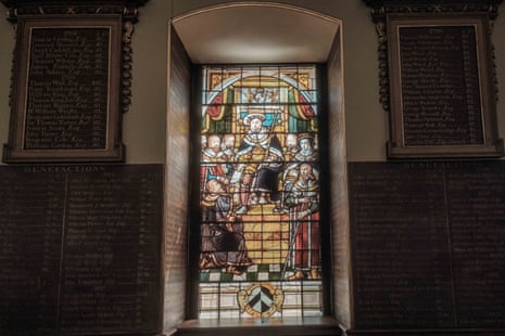 A stained glass window depicting a monarch in the Great Hall. Surrounding the window are more commemorative boards