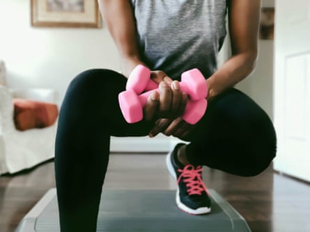 A woman uses dumbbells and aerobic step at home