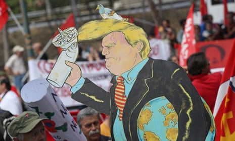 Demonstrators protest during the G7 summit with a Donald Trump placard created by Guglielmo Manenti.