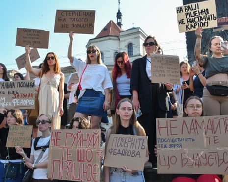 A group of women hold cardboard signs at an outdoor protest