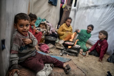 Palestinian children cook a meal in the middle of plastic tents in Rafah.