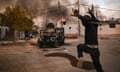 A man gestures as people loot in the Naja military housing complex in southeastern Damascus.