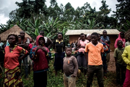 A group of Congolese people look on as the corpse of a suspected Ebola victim is picked up, in North Kivu province