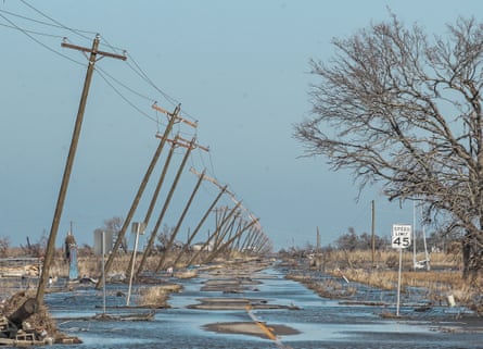 Utility poles lean along a flooded road in Cameron, Louisiana, in October 2020.