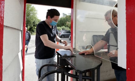 A football spectator buying a ticket at a screened turnstile