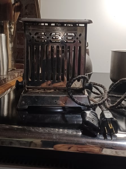 A very old metal toaster with black and white striped flex